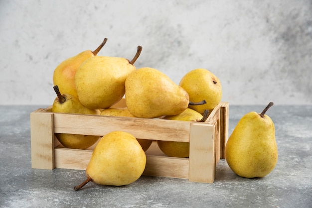 Stelletje verse bio-peren in houten kist op marmeren oppervlak.