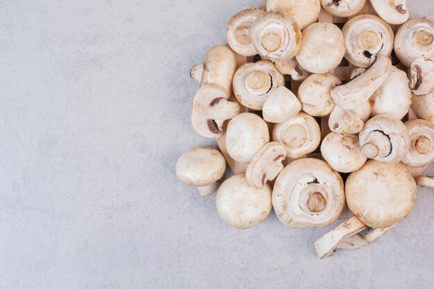 Stelletje verse champignons op marmeren tafel.