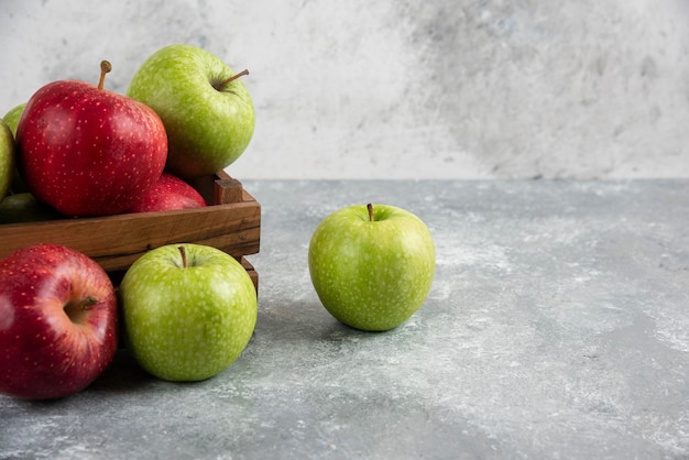 Stelletje verse groene en rode appels geplaatst in houten kist.