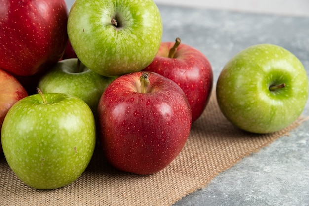 Stelletje verse groene en rode appels op jute geplaatst.