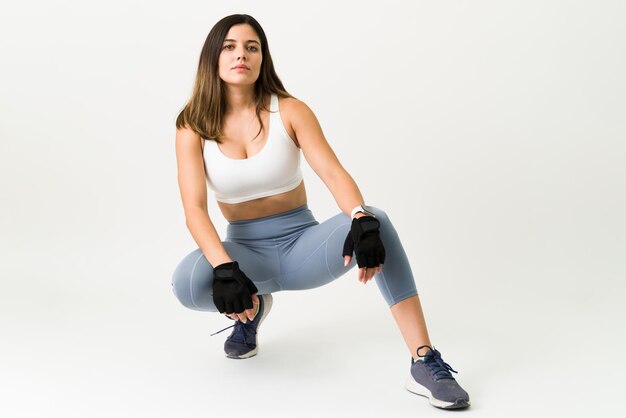 Sterke jonge vrouw die zich voordeed tegen een witte achtergrond. Sportieve vrouw in activewear staat op het punt te gaan sporten