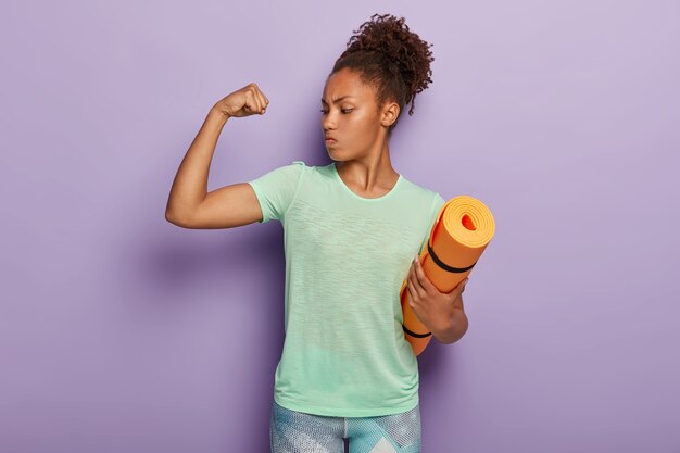 Sterke sportvrouw heeft fitnessoefeningen binnen, toont spieren na de training