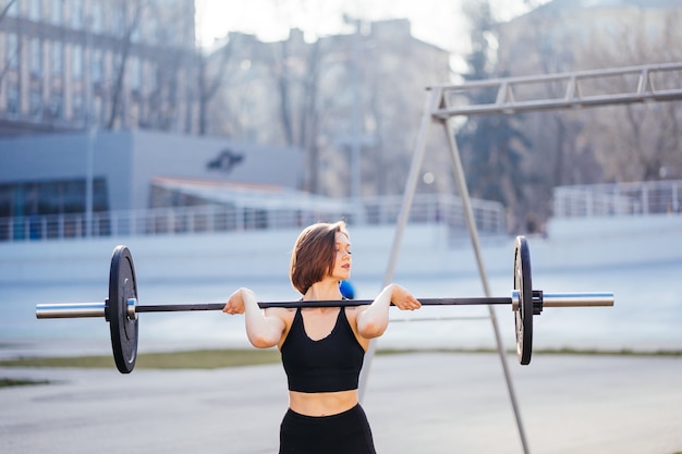 Sterke vrouw die met barbell uitoefent. Leuk meisje die voor gewichtheffentraining voorbereidingen treffen. Sport, fitnessconcept.