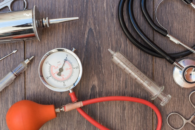 Stethoscoop; bloeddrukmeter en medische apparatuur op houten bureau