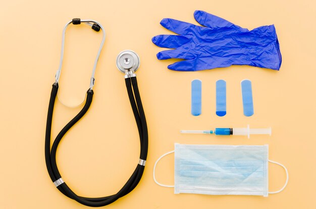 Stethoscoop; verfrommelde handschoenen; verbanden; spuit en chirurgische handschoenen op gele achtergrond