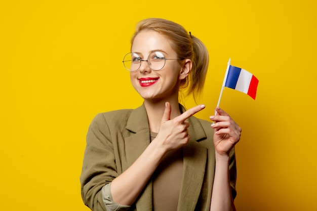Stijl blonde vrouw in jas met franse vlag op geel