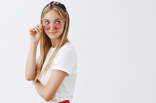 Gratis foto stijlvol aantrekkelijk jong blond meisje poseren tegen de witte muur