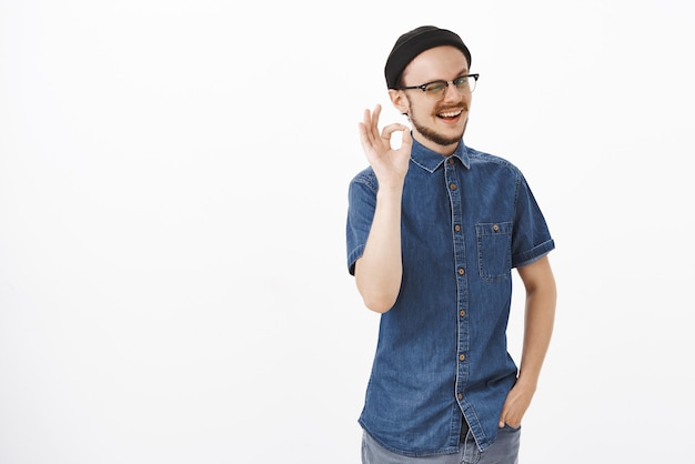 Stijlvol en vriendelijk ondersteunend mannelijk model met baard die knipoogt en vrolijk glimlacht en perfect of uitstekend gebaar toont