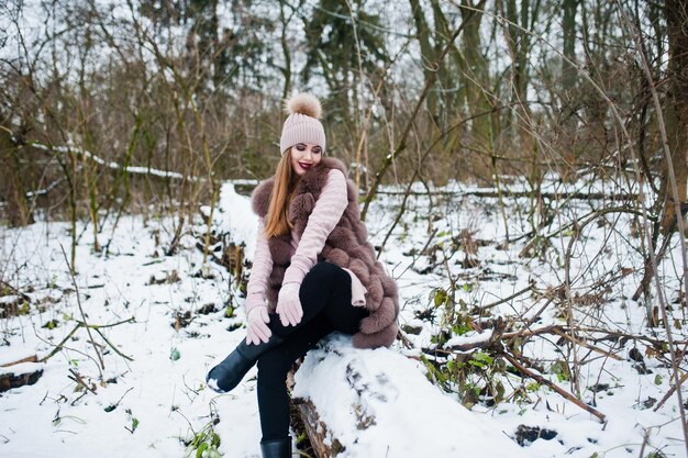 Stijlvol meisje in bontjas en hoofddeksels bij winterbos