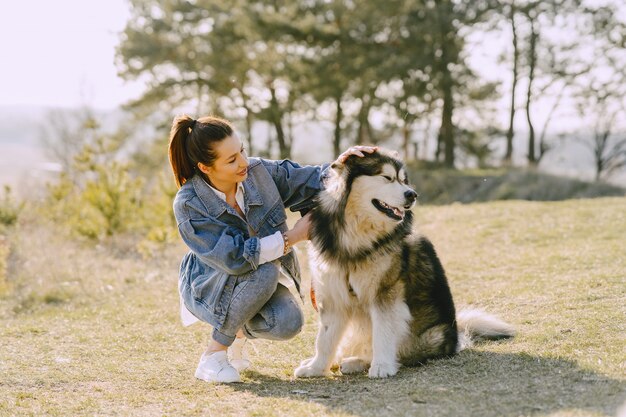 Stijlvol meisje in een zonnig veld met een hond