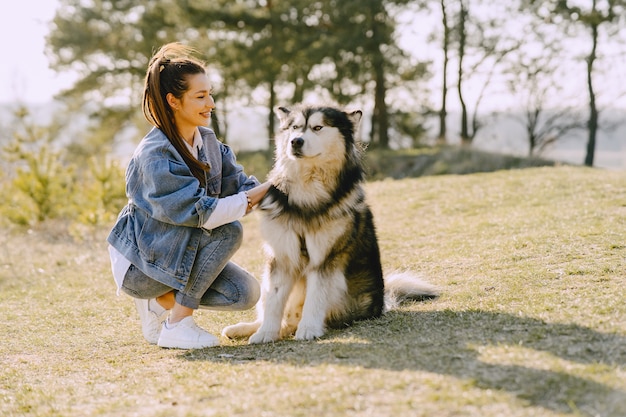 Stijlvol meisje in een zonnig veld met een hond