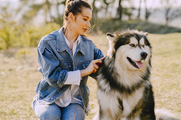 Stijlvol meisje in een zonnig veld met een hond