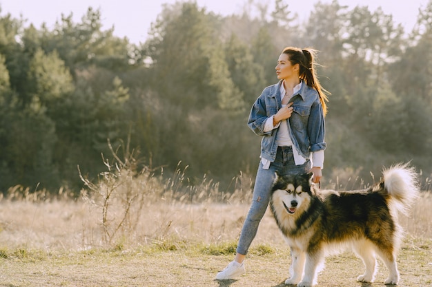 Stijlvol meisje in een zonnig veld met een hond