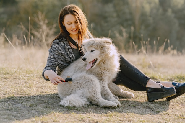 Stijlvol meisje in een zonnig veld met een hond