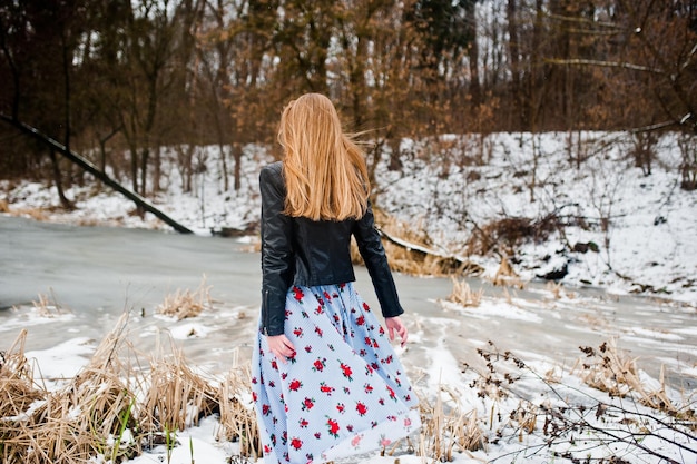 Stijlvol meisje in leren jas op winterdag tegen bevroren meer