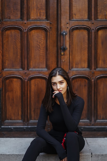 Stijlvolle brunette meisje, zittend op de trap