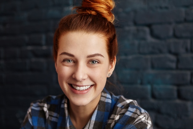 Gratis foto stijlvolle gelukkig jonge europese vrouw met gember haar en charmante glimlach op zoek