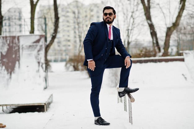 Stijlvolle Indiase baard zakenman in pak en zonnebril poseerde op winterdag buiten