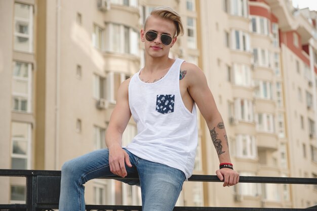 Stijlvolle jonge man met tatoeages en trendy kapsel