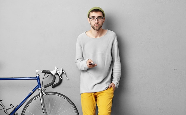 Stijlvolle jonge man permanent in de buurt van fiets