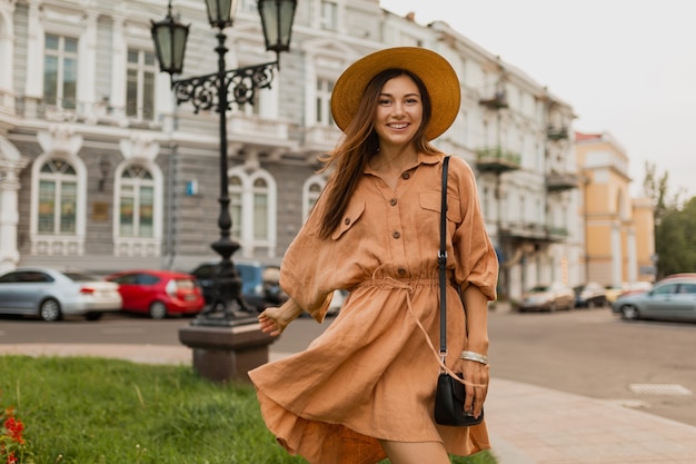 Stijlvolle jonge vrouw die in Europa reist, gekleed in een trendy lentejurk en accessoires die lacht en plezier heeft