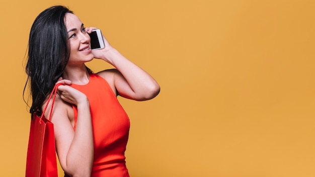 Stijlvolle jonge vrouw met tas chatten op telefoon