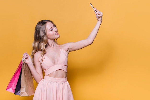 Gratis foto stijlvolle jonge vrouw met tassen selfie te nemen