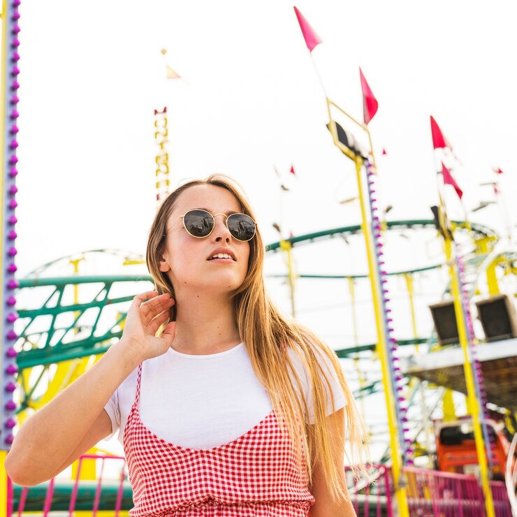 Gratis Foto stijlvolle jonge vrouw staande voor achtbaan