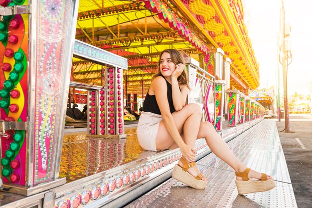 Stijlvolle jonge vrouw zitten in de buurt van de kermis rit