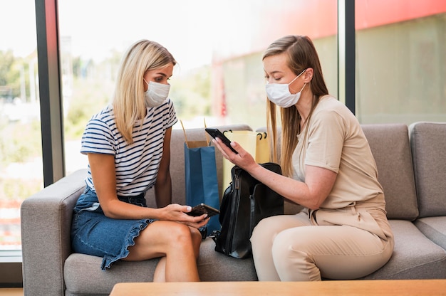 Gratis foto stijlvolle jonge vrouwen die mobiele telefoon doorbladeren