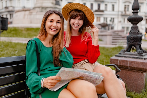 Stijlvolle jonge vrouwen die samen reizen in europa, gekleed in trendy lente-outfit en accessoires met kaart