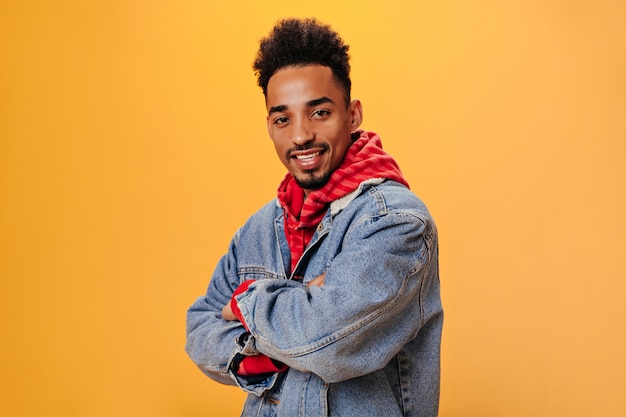 Stijlvolle man in denim outfit poseren op oranje muur