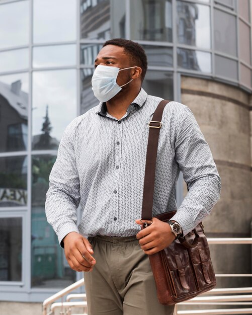 Stijlvolle man met masker op weg naar zijn werk tijdens pandemie
