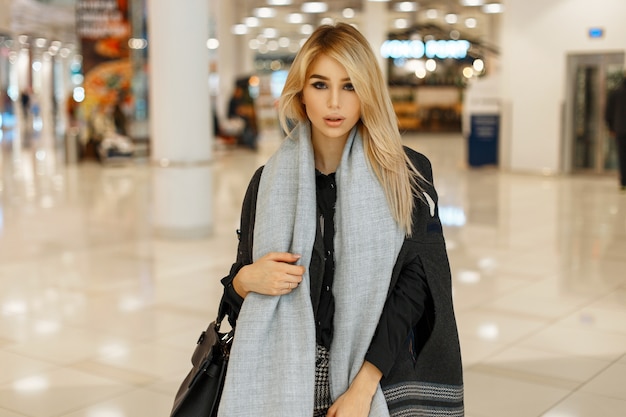 Stijlvolle mooie jonge vrouw in trendy herfstjas met sjaal winkelen