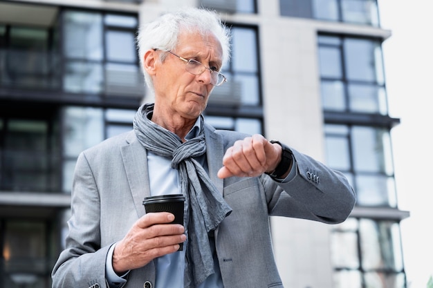 Stijlvolle oudere man in de stad die naar smartwatch kijkt