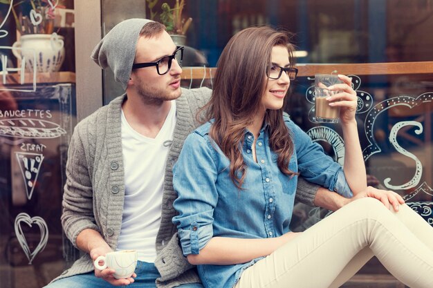 Stijlvolle paar zitten met kopje koffie buiten het café