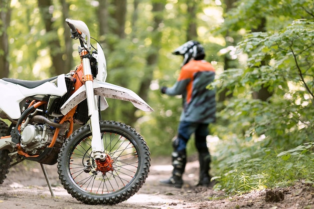 Stijlvolle rijder met motor geparkeerd in het bos