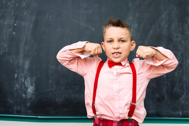 Stijlvolle schooljongen poseren op schoolbord