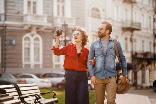 Stijlvolle verliefde paar wandelen omarmen in straat op romantische reis en het nemen van foto