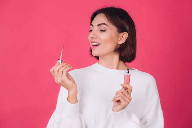 Stijlvolle vrouw in casual witte trui op roze rode muur