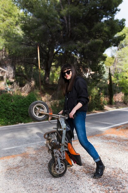 Stijlvolle vrouw speelt met kleine motorfiets
