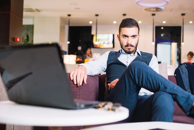 Gratis foto stijlvolle zelfverzekerde zakenman poseren op de bank