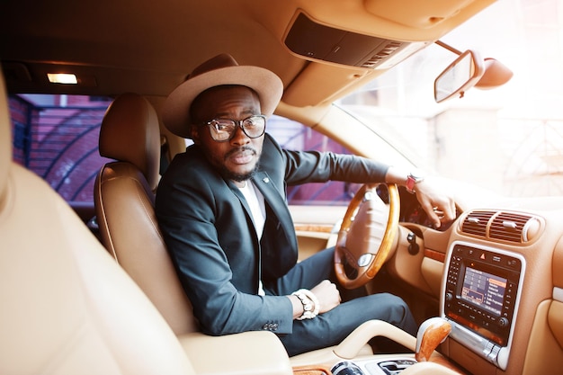 Stijlvolle zwarte man zit achter het stuur van een luxe auto Rijke Afro-Amerikaanse zakenman