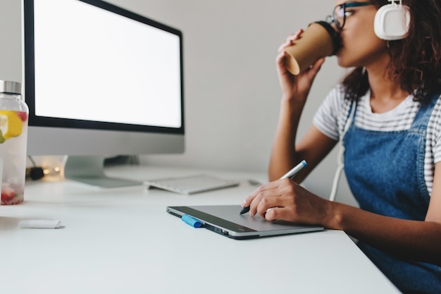 Stijlvolle zwarte meid in glazen koffie drinken met plezier tijdens het gebruik van tablet