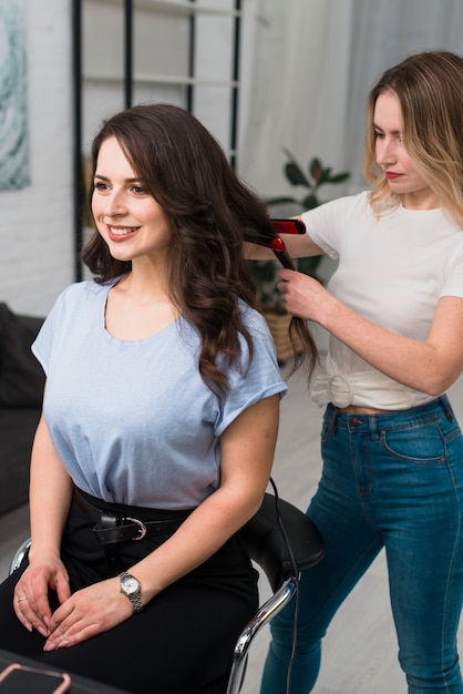 Gratis foto stileer krullend haar van jonge vrouw