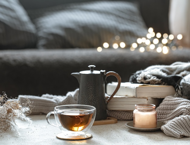 Stilleven met een kopje thee, een theepot, boeken en een kaars in een kandelaar met bokeh.