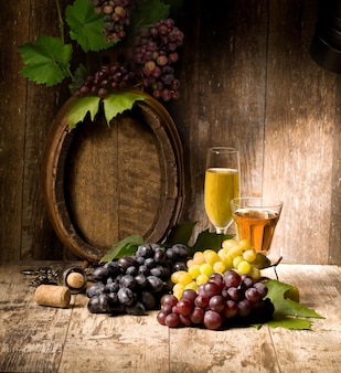 Stilleven met rode en witte wijn, glazen, druiven en vat