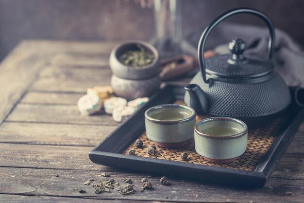 Stilleven van japanse gezonde groene thee in een kleine kopjes en theepot over donkere achtergrond