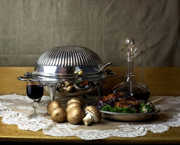 Stillevenfoto van karaf en glas port, antieke komfoor, champignons en geroosterde kip