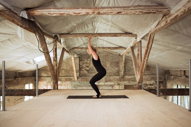 Gratis foto stilte. een jonge atletische vrouw oefent yoga op een verlaten bouwgebouw. geestelijke en lichamelijke gezondheid. concept van een gezonde levensstijl, sport, activiteit, gewichtsverlies, concentratie.